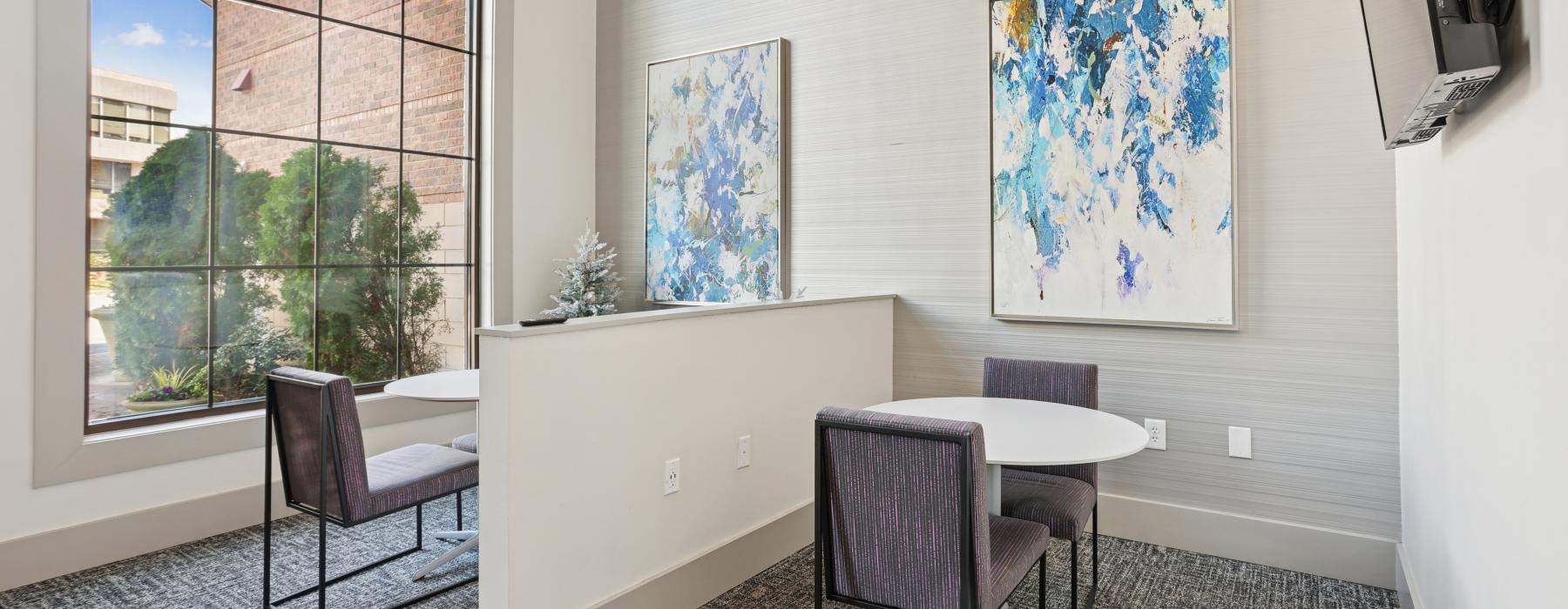 a room with a table chairs and a window with a view of the city